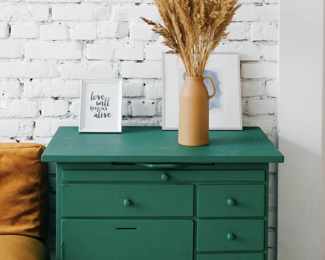 A green furniture in a white painted room having 2 frames and a base on top of it